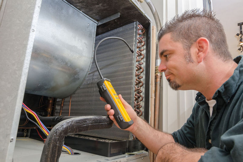 HVAC technician with leak detector