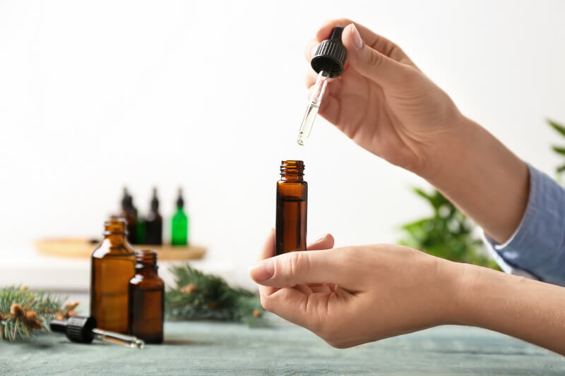 Woman dripping essential oil into a glass bottle